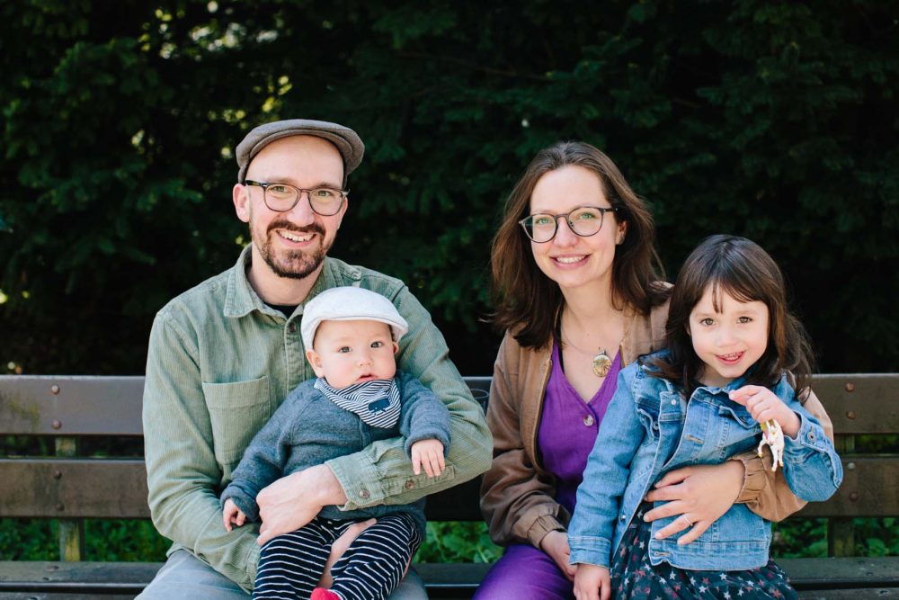 Eltern und zwei Kinder sitzend und lachend auf einer Bank