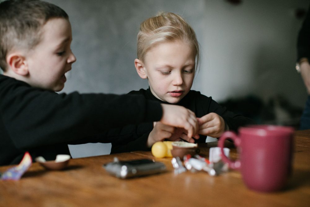 Zwei Jungs basteln Überraschungsei am Tisch zusammen