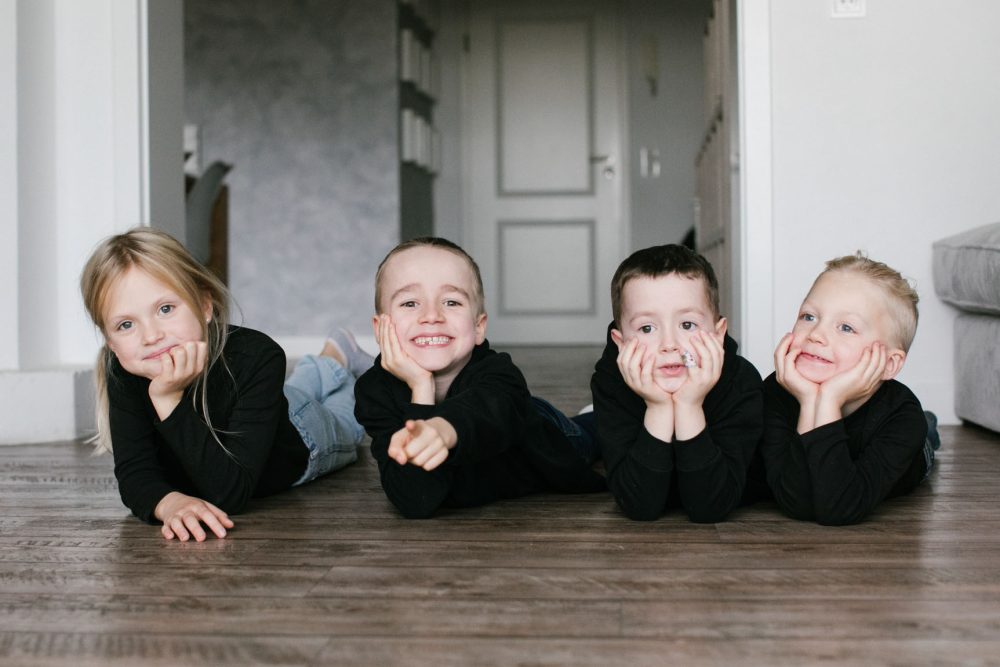 Vier Kinder liegen auf dem Boden